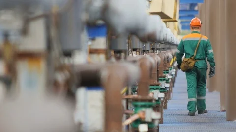 Backside View Worker in Green Uniform Walks along Pipelines Stock Footage 81370493