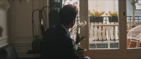 Backside of a young man standing up walking toward a balcony Stock Footage 203585837