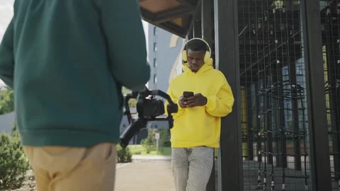 Backstage. Operator takes video of young african man in yellow headphones and Video stock 244268705