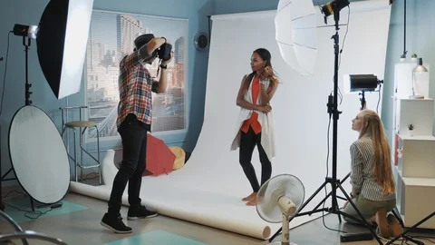 Backstage of the photo session in modern studio: assistant adjusting the Stock Footage 122586633