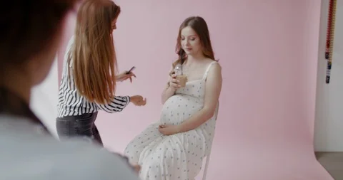 Backstage of the photo shoot: Beautiful caucasian pregnant model sits on studio  Stock Footage 113069853