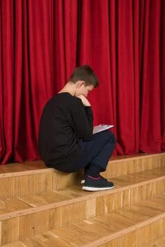 Backstage at the stage, a young actor is carefully studying his script Stock Photos