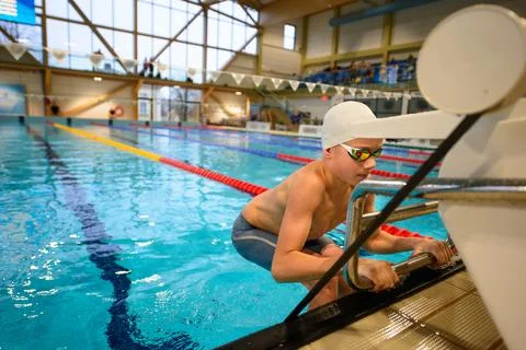 Backstroke swimmer boy start from the starting table in the pool Stock Photos