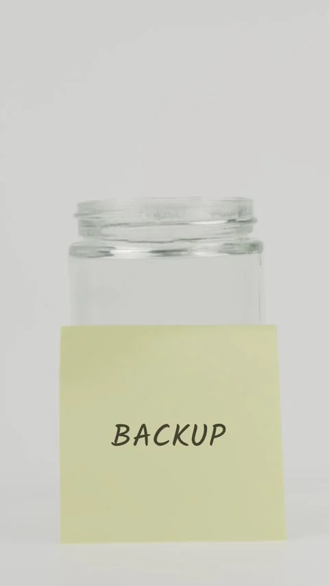 Backup text or word on yellow sticky note attached to glass jar with hand Stock Footage 311680091