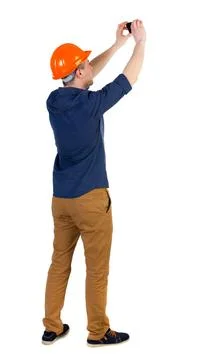 Backview of an engineer in construction helmet stands and using Backview o... 写真素材