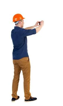 Backview of an engineer in construction helmet stands and using Backview o... 写真素材