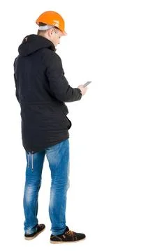 Backview of an engineer in construction helmet stands and using Backview o... 库存照片