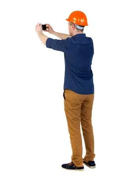 Backview of an engineer in construction helmet stands and using Backview o... 库存照片
