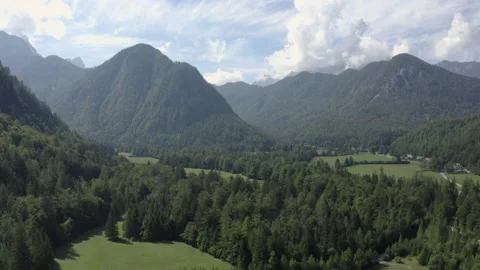 Backward aerial flight over a mountain valley with meadows. Video stock 217374513