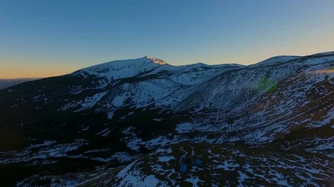 Backward aerial top view over winter snowy mountain and woods forest at sunset Video stock 101030797