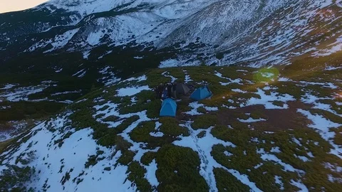 Backward aerial top view over winter snowy mountain and woods forest at sunset 動画素材 101031031