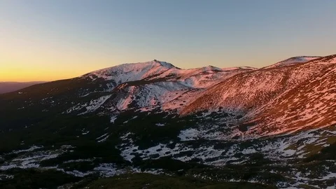 Backward aerial top view over winter snowy mountain and woods forest at sunset 動画素材 101031128