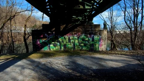 Backward dolly moving under iron railway bridge pillar Stock Footage 123927598