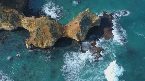 Backward flight with camera tilt upwards over eroding rock formations on ocea Video stock 107487304