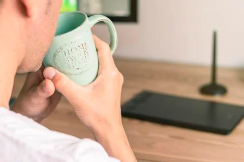 Backward man sitting at the computer and drinking from a cup. Stock Photos