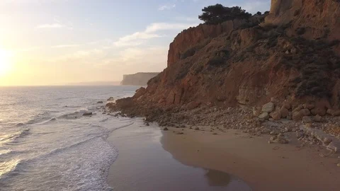 Backward moving drone shot over ocean and cliffs at sunset Vidéo 98371250