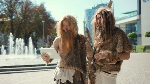 Backward primitive neanderthals using tablet pc in the street. Two aggressive Video stock 116908793