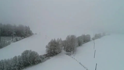 Backwards drone dolley shot during a snow shower and fog over a winters Video stock 234594937