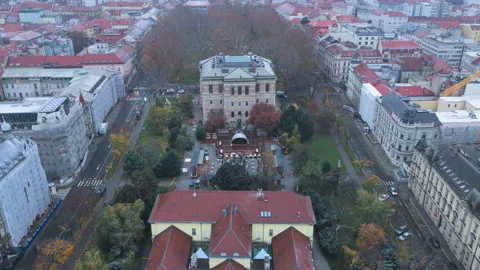 Backwards drone flight over historic HAZU buildings and street in snowy Zagreb Stock Footage 321648092