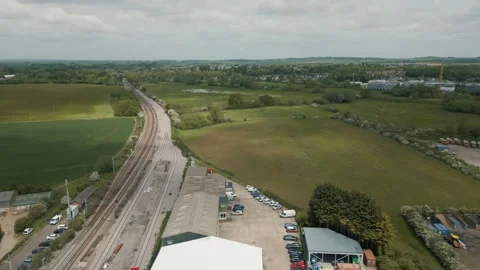 Backwards drone shot revealing train tracks and a train station with cars Stock Footage 296803226