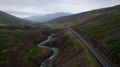 Backwards flying aerial shot in dramatic Iceland landscape with car below. Video stock 166557967