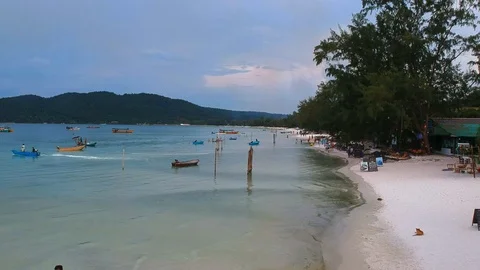 Backwards moving drone view of island coast and tourists relaxing in the sea Stock Footage 111285225