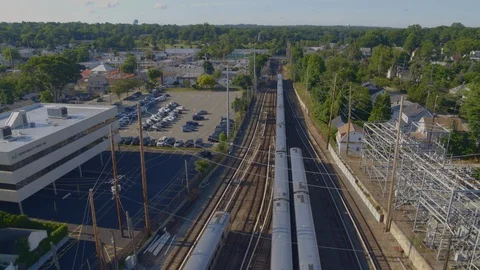 Backwards Pan Tilt Up of Train Leaving Station and Passing Through a Small Town Stock Footage 113009572