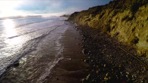Backwards tracking as waves crash in marine layer sunset at Malibu Beach Drone Stock Footage 174907388