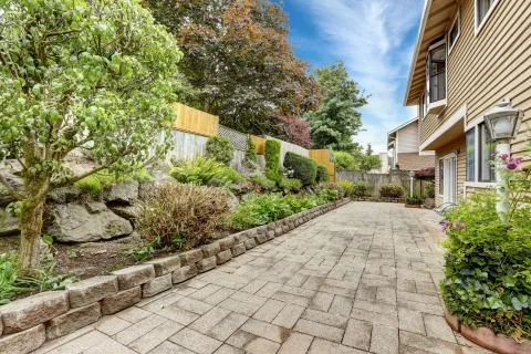 Backyard area with stone tile floor and beautiful flower bed Stock Photos