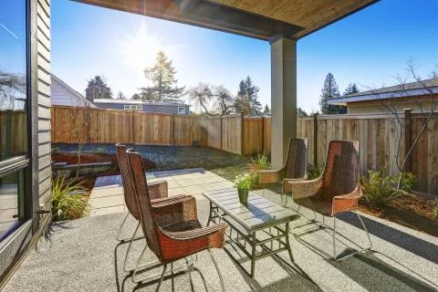 Backyard covered patio design with high back wicker chairs on a sunny day. Stock Photos