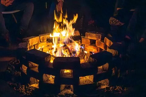 Backyard fire pit emits light and heat causing people to gather and interact in Stock Photos