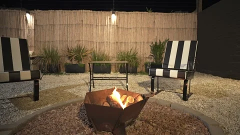 Backyard Patio Fire Pit with Black and White Striped Lounge Chairs at Night Video stock 339059685