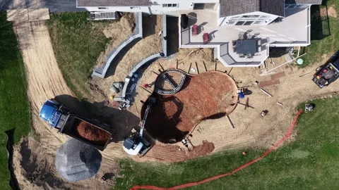 Backyard pool construction in a US suburban neighborhood, showing excavator Stock Footage 333688349