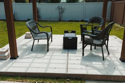 A backyard seating area shows two chairs and a small table on concrete. Grass 스톡 사진