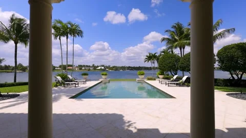 Backyard Surrounded by vegetation, lounge chairs, tile floor, pool and Sky. Stock Footage 239178843