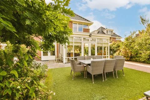 A backyard with a table and chairs and a house Stock Photos