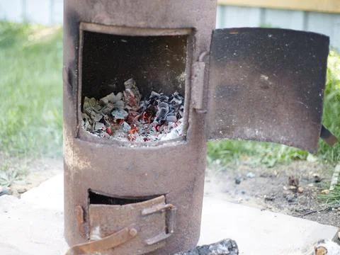 In the backyard there is a rusty oven with an open door for cooking Uzbek pil Stock Photos