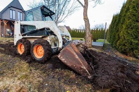 Backyard tree removal with skid steer beside modern wood house Stock-Fotos