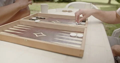 In the backyard, two friends play backgammon outdoors, spending quality time Stockbeeldmateriaal 282321851