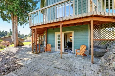Backyard view of waterfront home with green siding and wraparound deck  Stock Photos