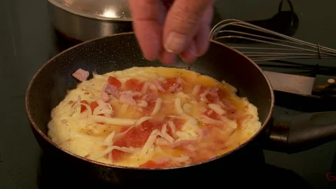 Bacon added to cooking omelette Stock Footage 130797403