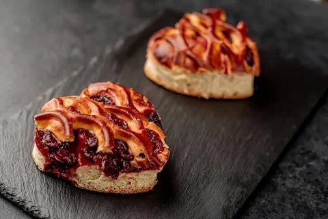 Bacon and berry jam on bread slices on black slate Stock Photos
