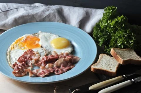 Bacon and eggs on a blue plate, toast Stock Photos
