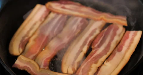 Bacon beginning to cook and steam in cast iron skillet. Stock Footage 138332984