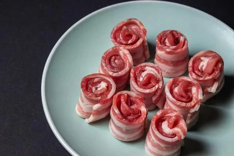 Bacon on a black background. Raw bacon on a plate Stock Photos