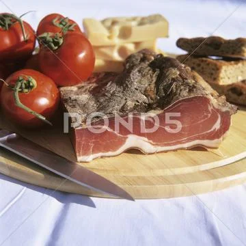 Bacon, cheese, tomatoes and bread on board Stock Photos