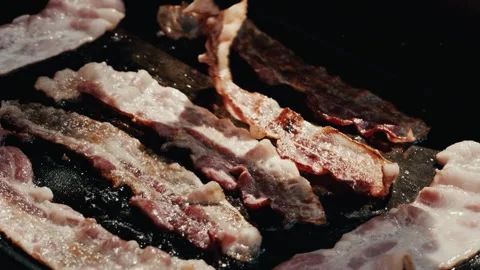 Bacon cooking on flat top flipped with tongs Stock Footage 280602896