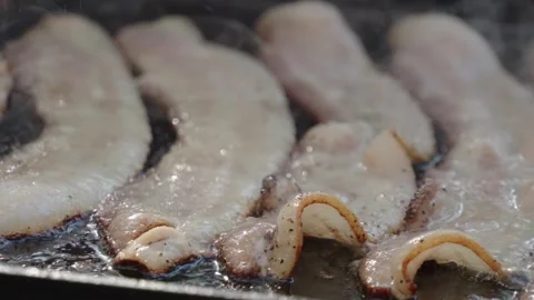 Bacon cooking on a flat top grill outside close up Stock Footage 310253746