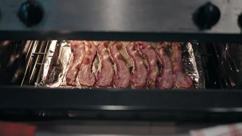 Bacon cooking in the oven on a foil lined baking sheet Stock Footage 340281733
