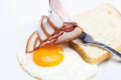 Bacon with  fried  eggs on a plate, fork and bread isolated on white Stock Photos